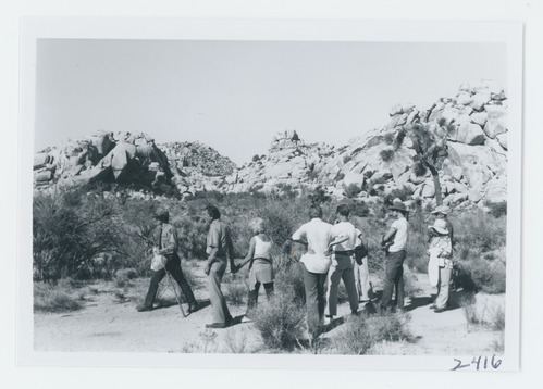 Black and white image of Conducted hike in Barker Dam area. Reino Clark leading visitors.