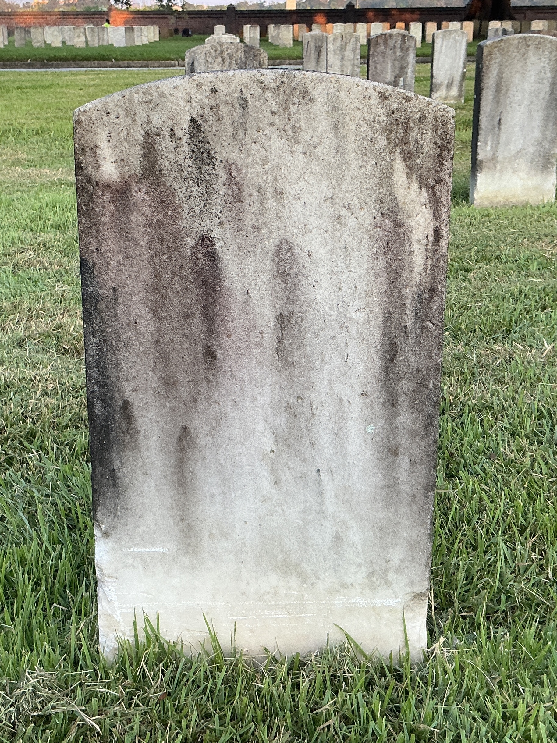 Back of historic upright marble headstone with recessed shield face.