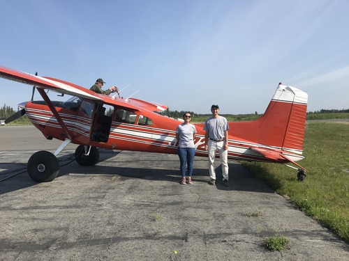 2 people standing next to a small plane