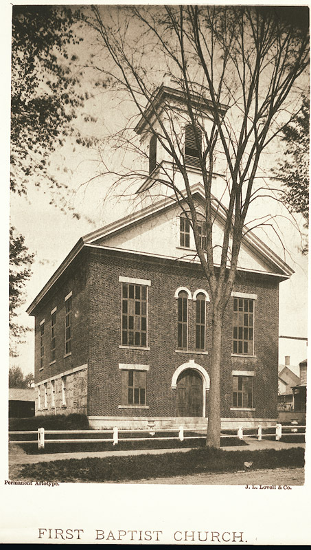 View of the First Baptist Church on South Pleasant Street with a white fence in the foreground. 