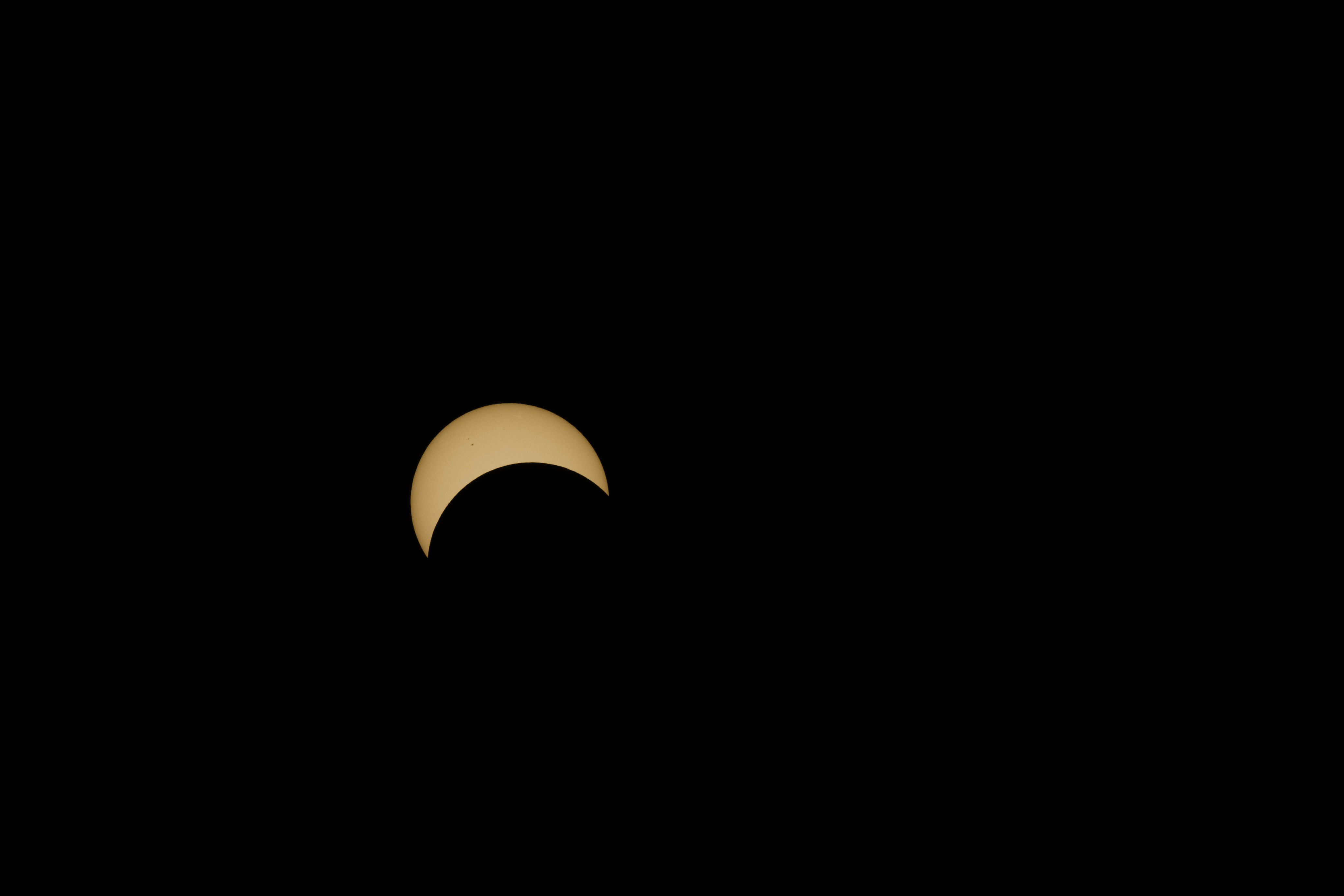 The moon covers the lower right half of the sun during part of the solar eclipse.