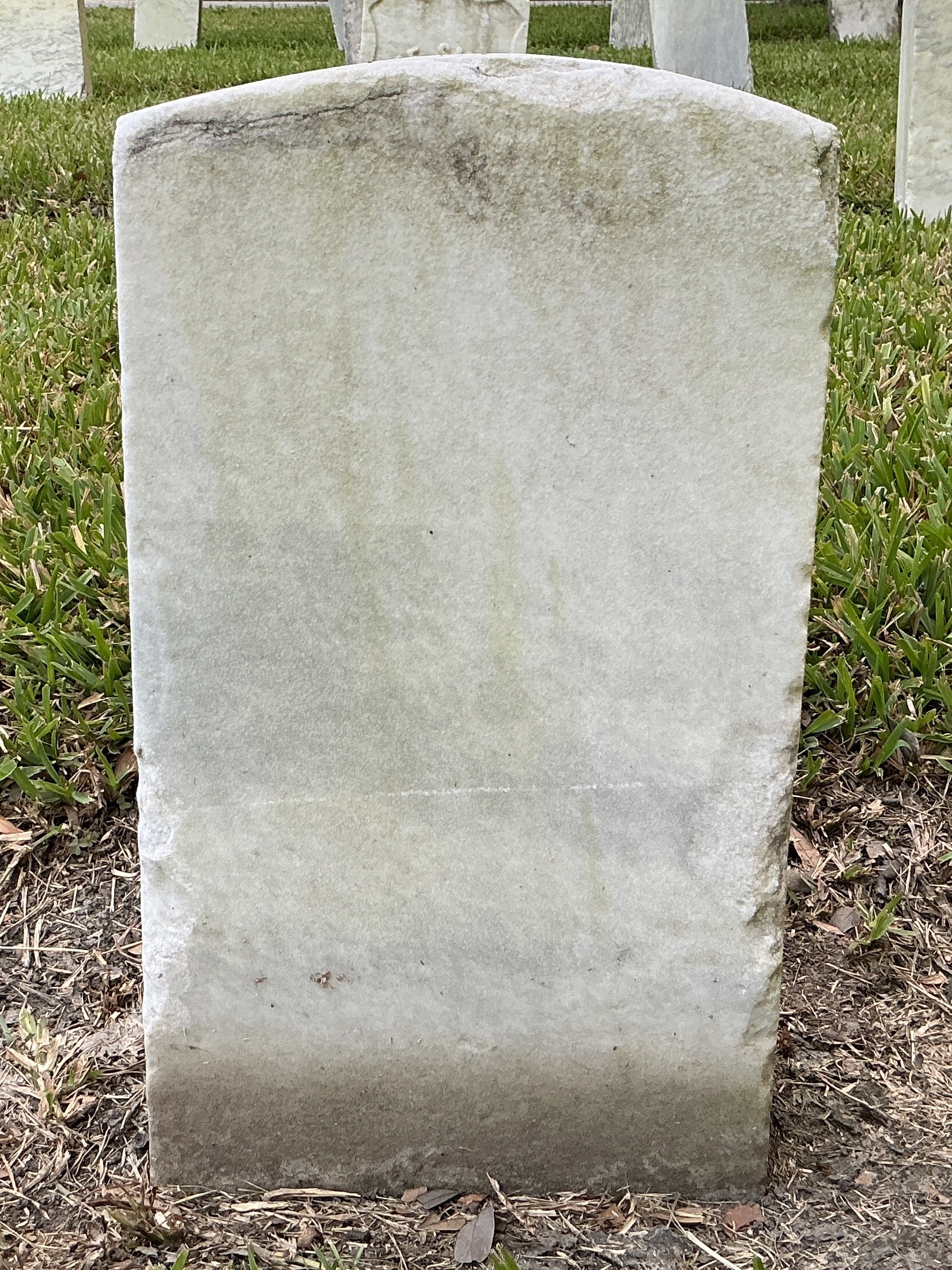 Back of historic upright marble headstone with recessed shield face.