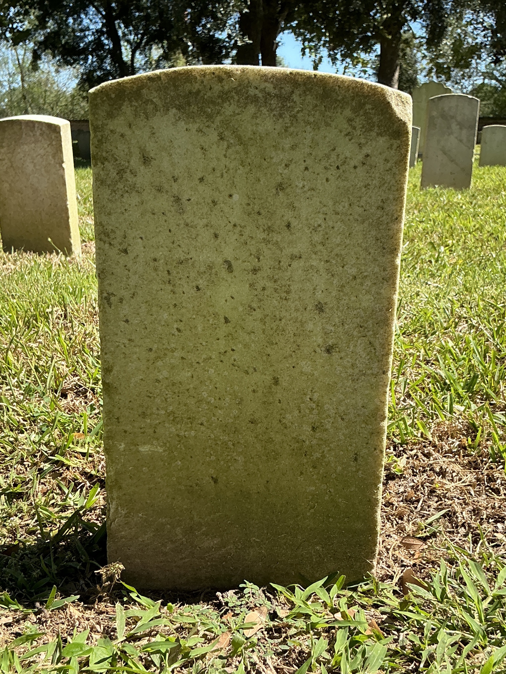 Back of historic upright marble headstone with recessed shield face.