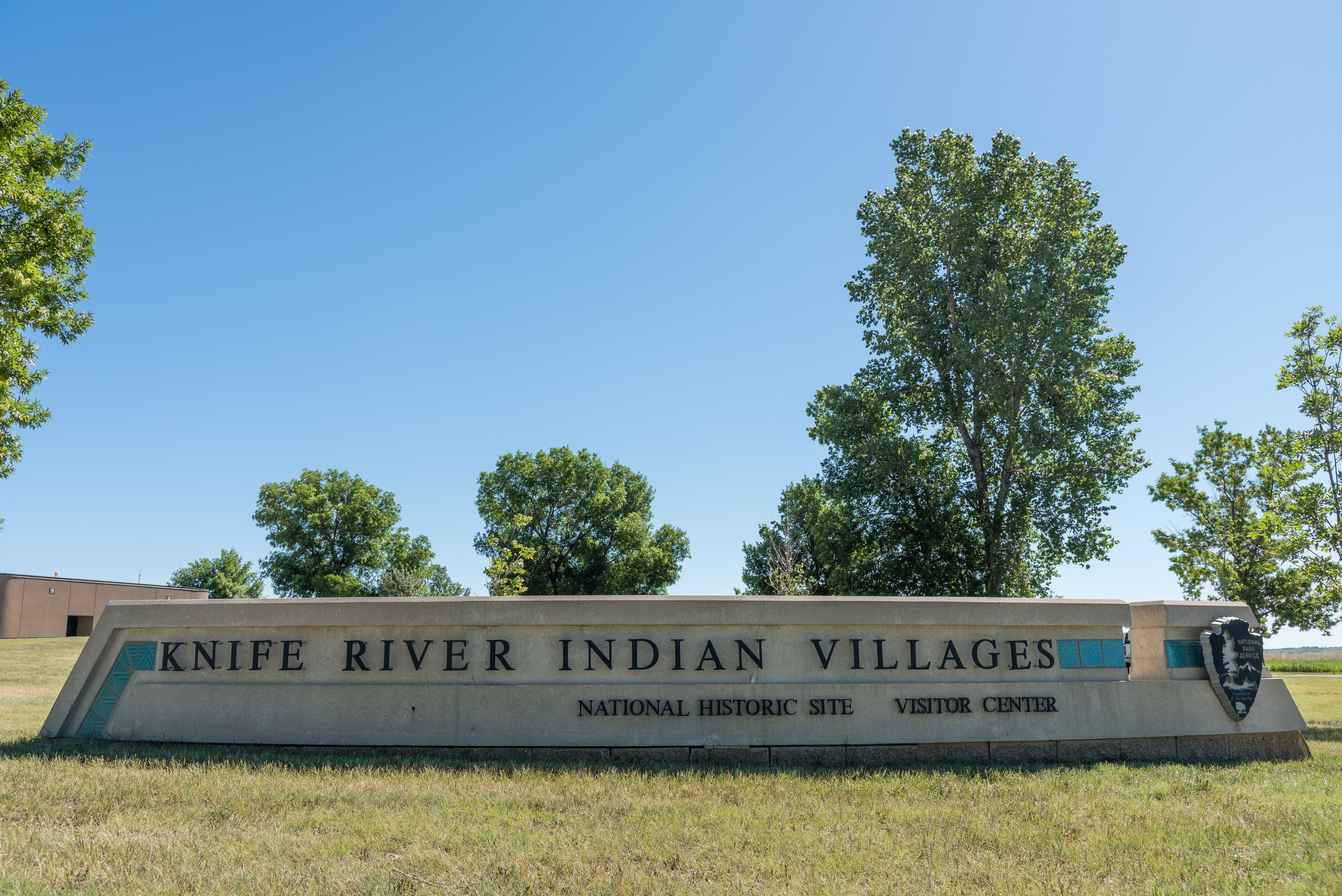 Entrance sign Knife River Indian Villages National Historic Site Visitor Center with National Park Service Arrowhead logo.