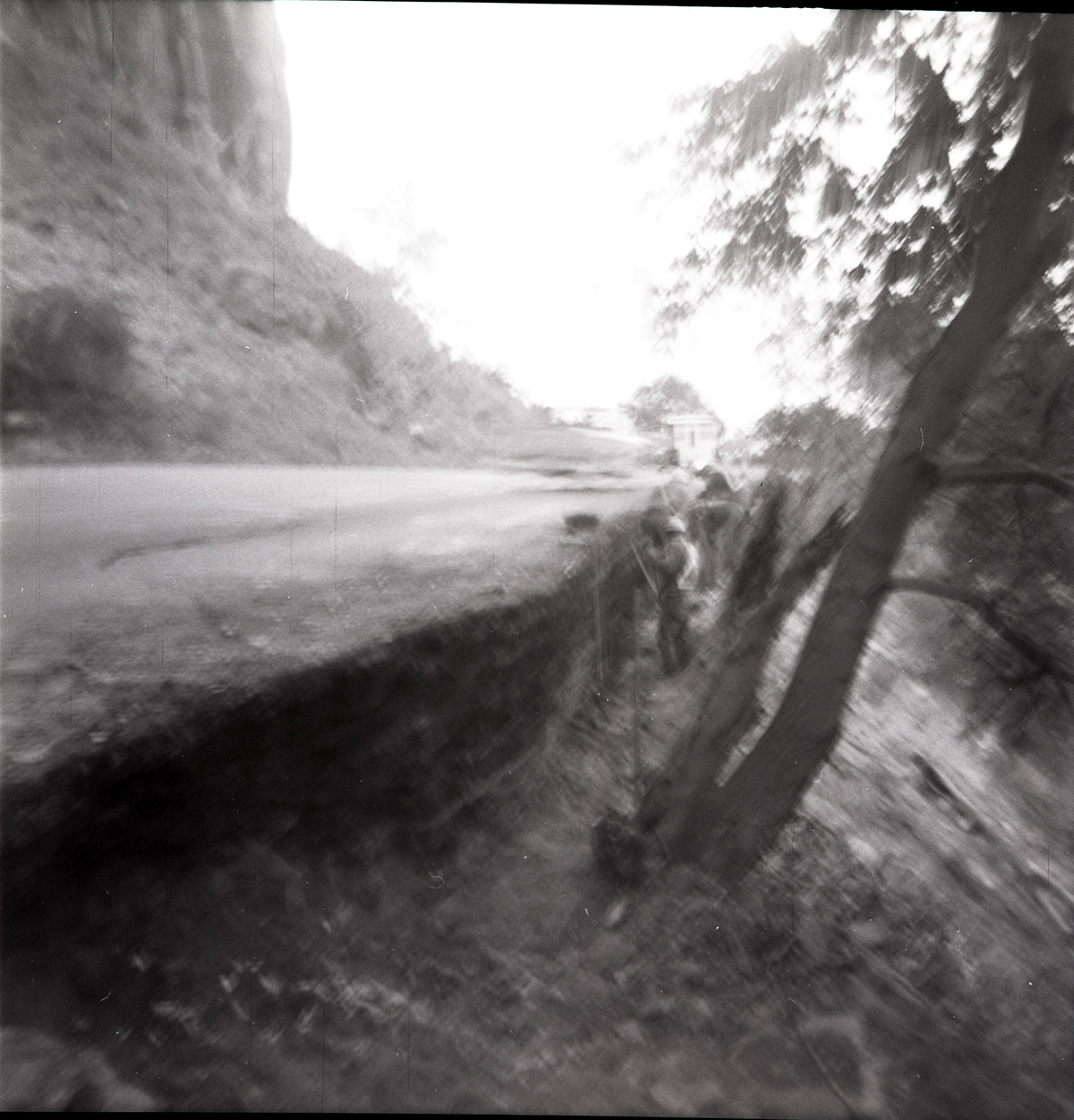 Men working on rebuilding rock retaining wall alongside road at the tunnel.
