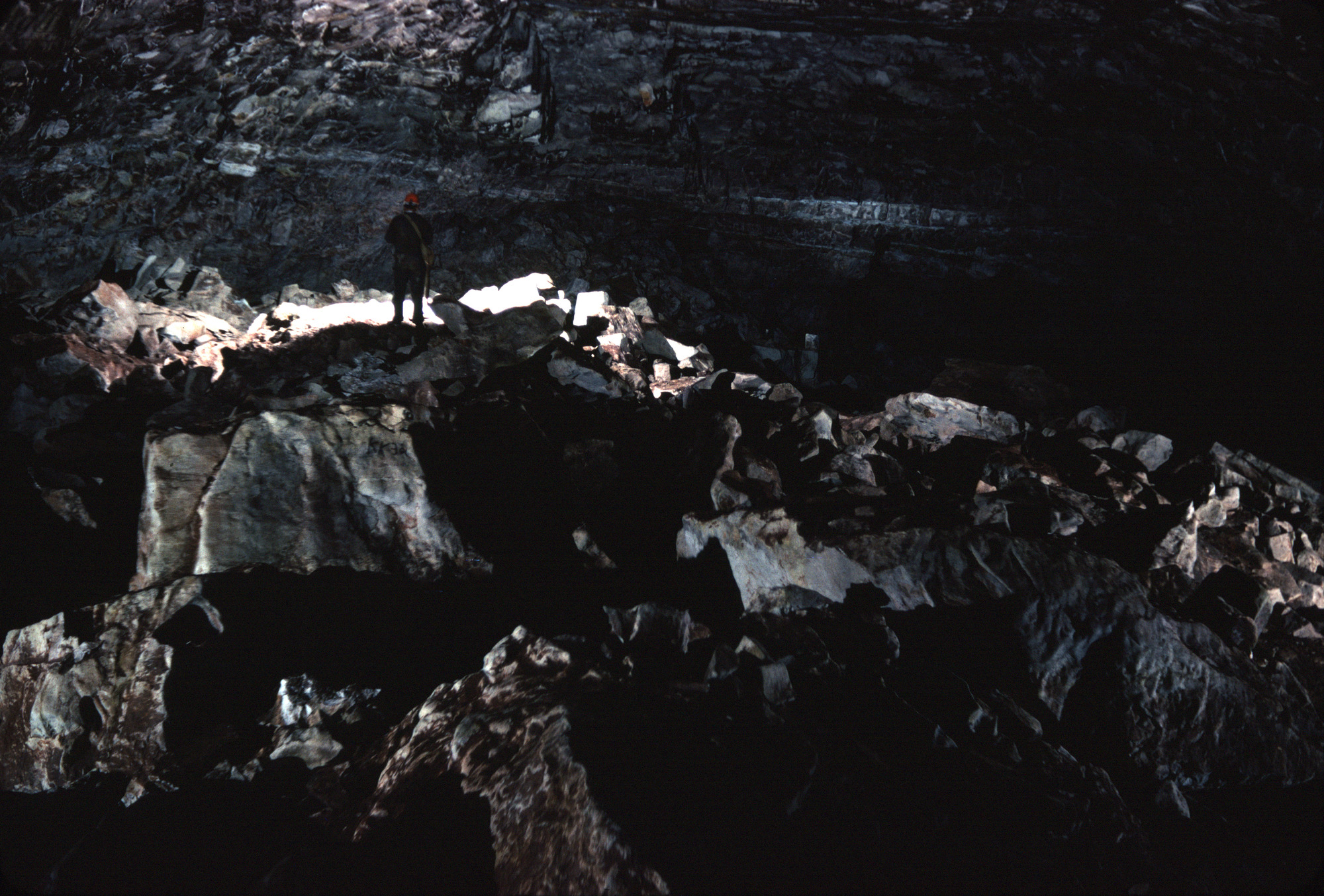 Caver standing inside large room with breakdown throughout