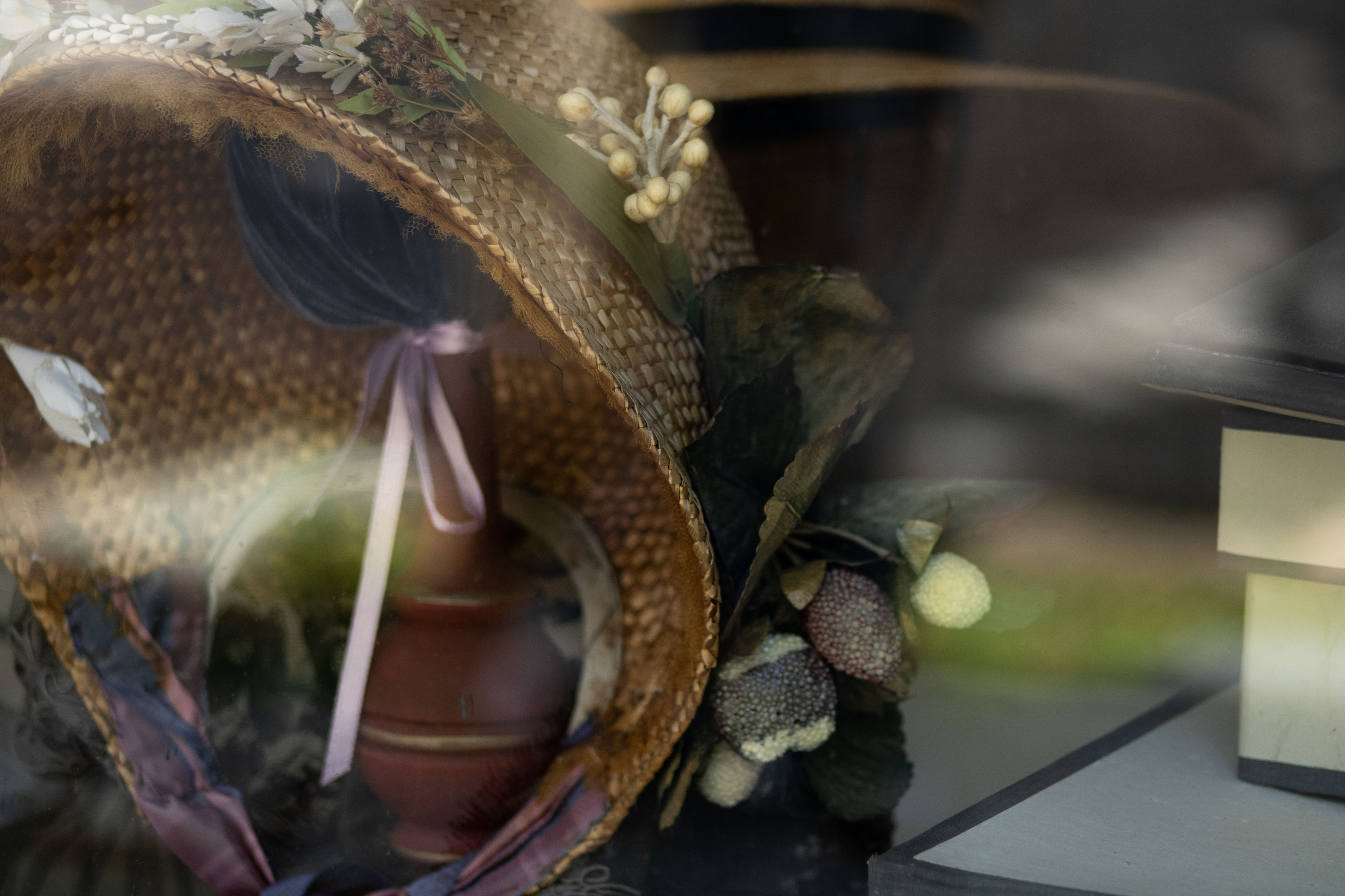 A photo of an antique bonnet in Harpers Ferry store front window. 