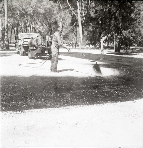 Man spraying layer of asphalt during construction for the Grotto parking area.