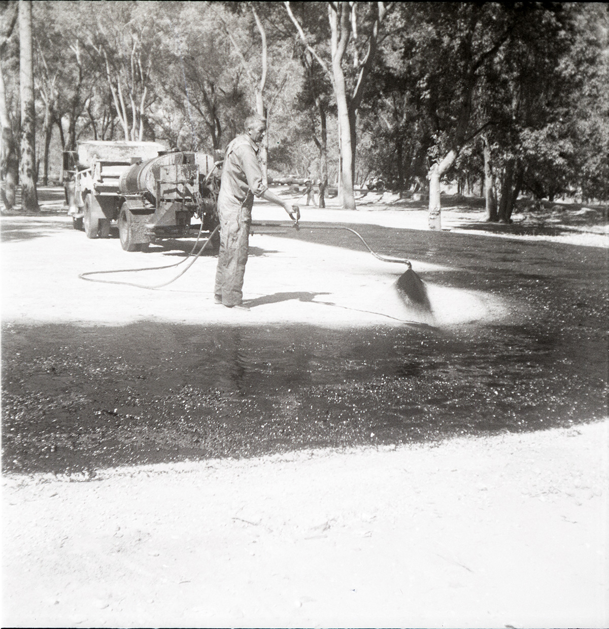 Man spraying layer of asphalt during construction for the Grotto parking area.