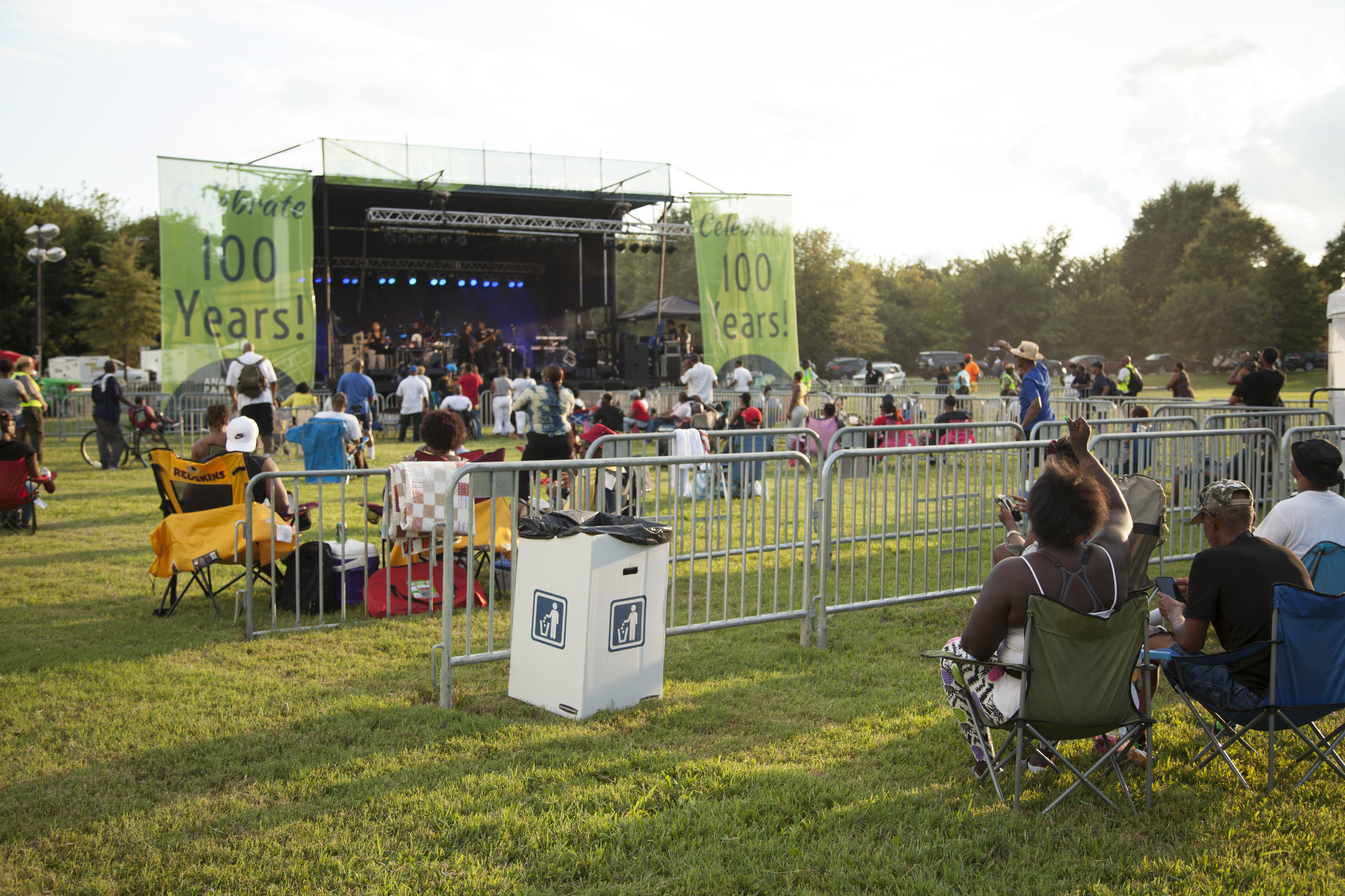 Several visitors sit in lawn chairs watching the concert from afar. 