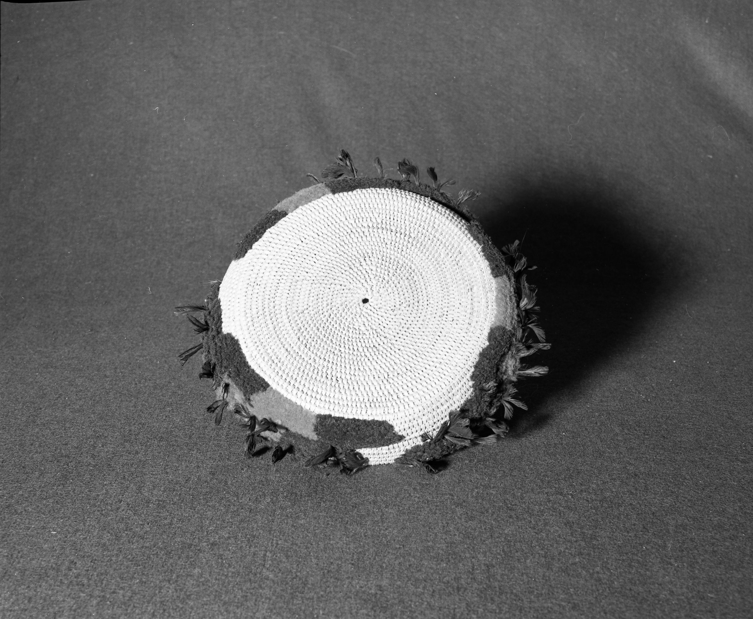 Marie Rozier Collection, Catalog No. 66. Object: Miwok decorated basket. Dimensions: 10" diameter x 1 1/2" height. Materials: Grass, split shoots, wool yarn, quail topknots. Technology: Single rod, rightward coil direction, fag ends trimmed on work face, moving ends trimmed on interior, interlocking stitch, clockspring start. Collection History: Once the property of Carmelita Ralph, sister of Mrs. Fuentes. Acquired from Dottie McDow. Photographed by Michael Dixon in December 1982. Catalogued by Craig Bates and Barbara Beroza. Yosemite Collections, National Park Service.