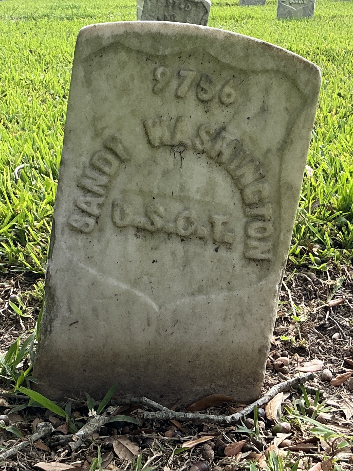 Front of historic upright marble headstone with recessed shield with recessed lettering face.