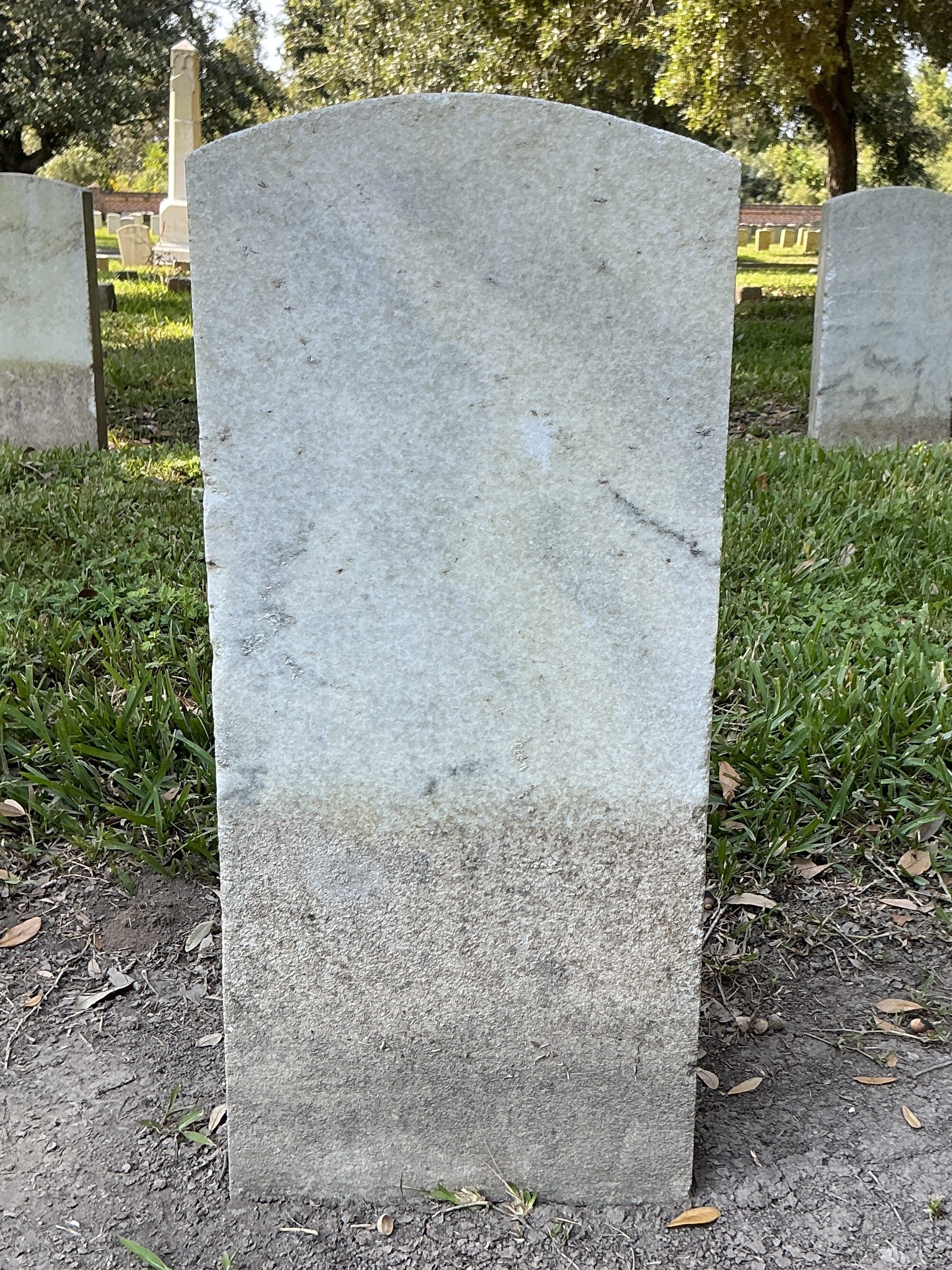 Back of historic upright marble headstone with recessed shield face.