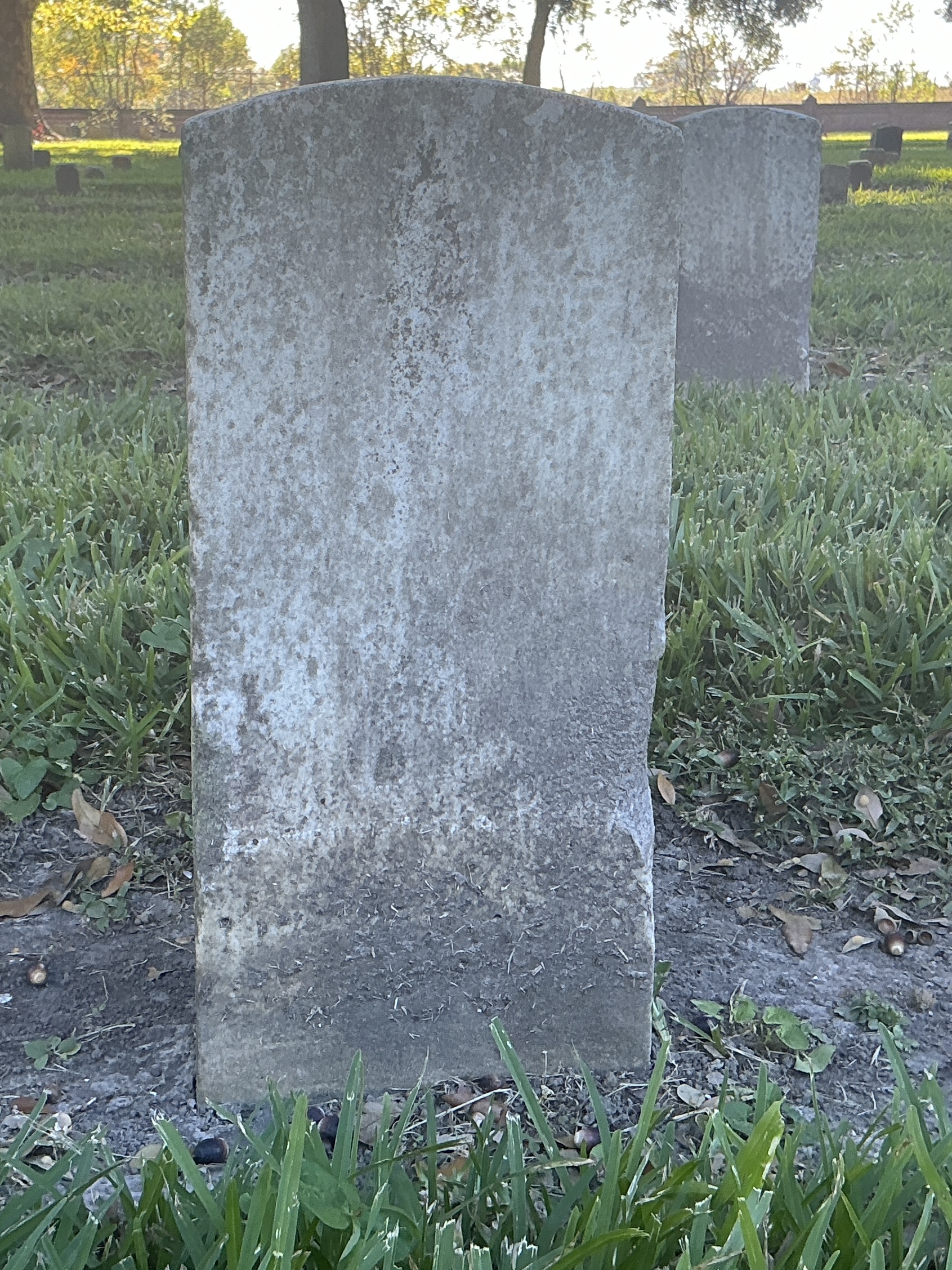 Back of historic upright marble headstone with recessed shield face.