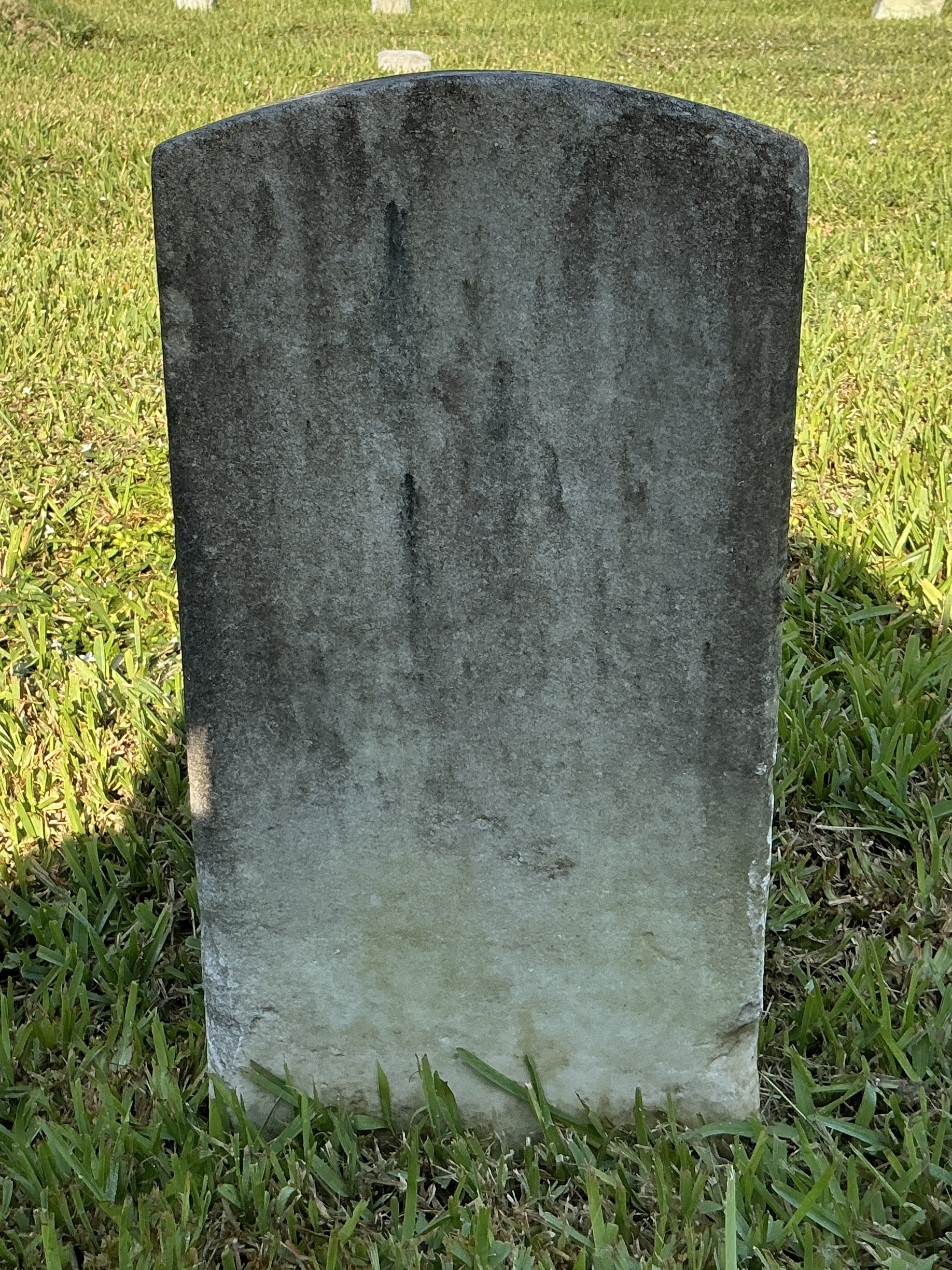 Back of historic upright marble headstone with recessed shield with recessed lettering face.