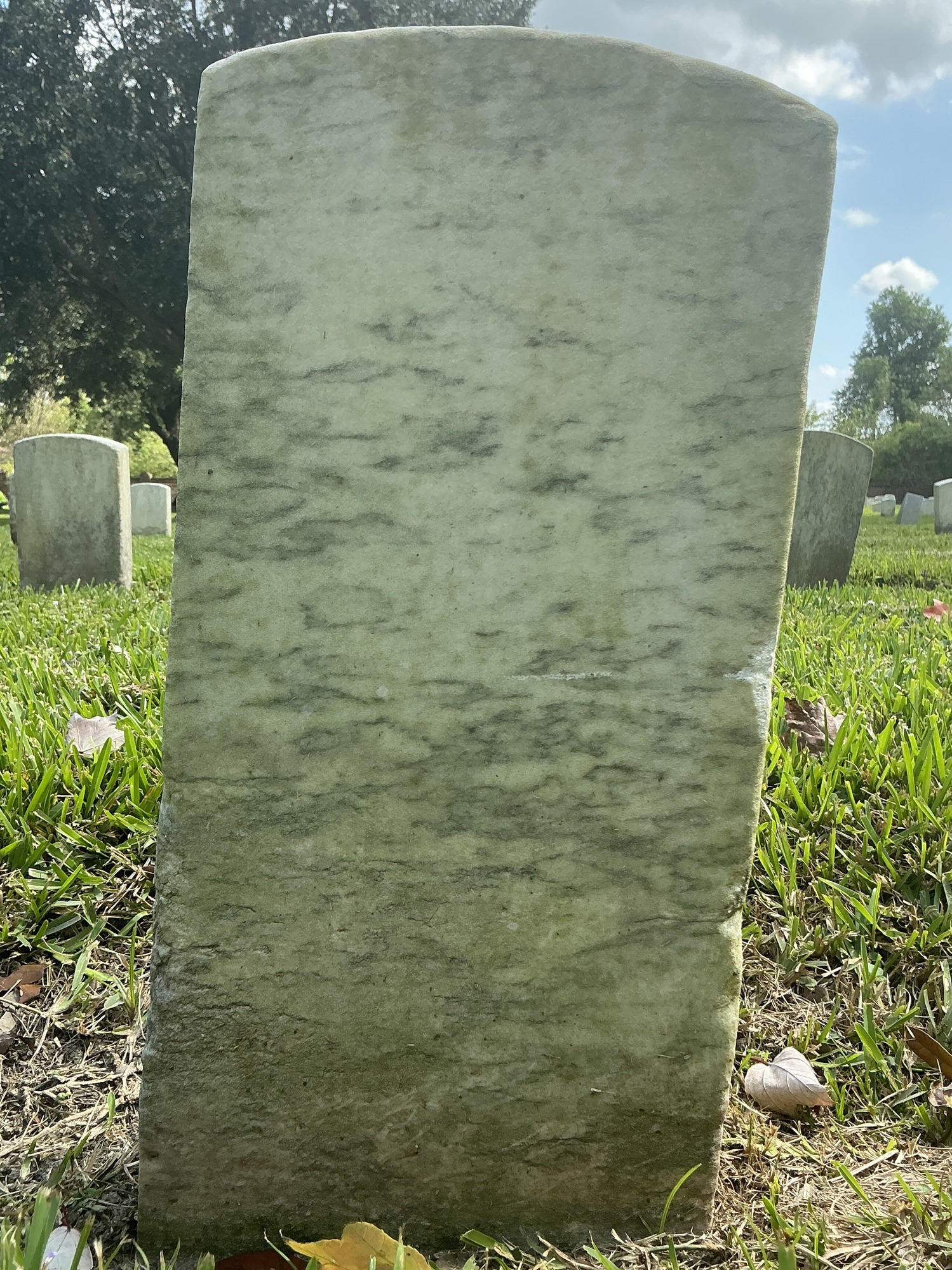 Back of historic upright marble headstone with recessed shield face.