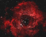 Deep space view of a scarlet colored, rosette nebula framed by stars as photographed from Big Bend National Park, Texas.