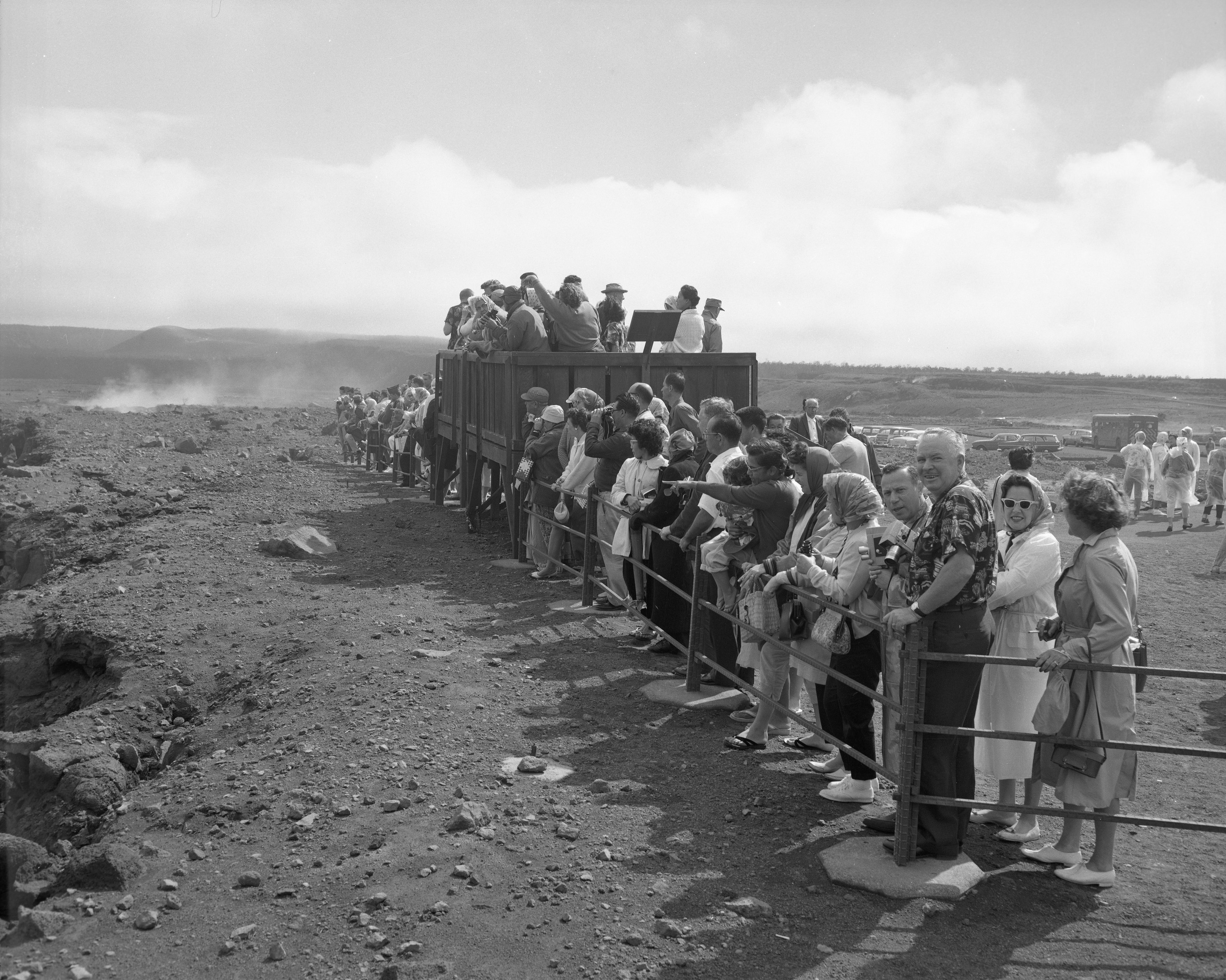 Black and white photo of people behind a railing and a platform on the edge of a volcanic crater