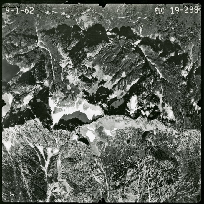 Black and white aerial photograph of glaciated mountain peaks and valleys.