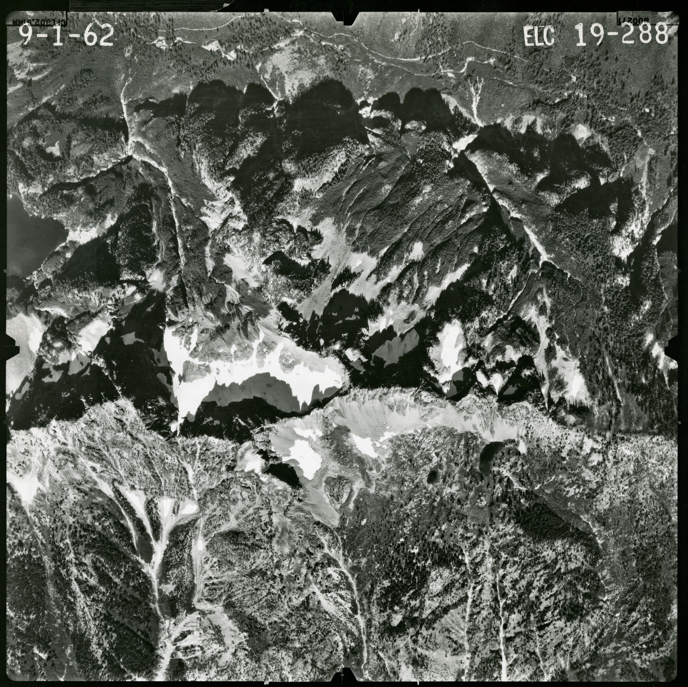 Black and white aerial photograph of glaciated mountain peaks and valleys.