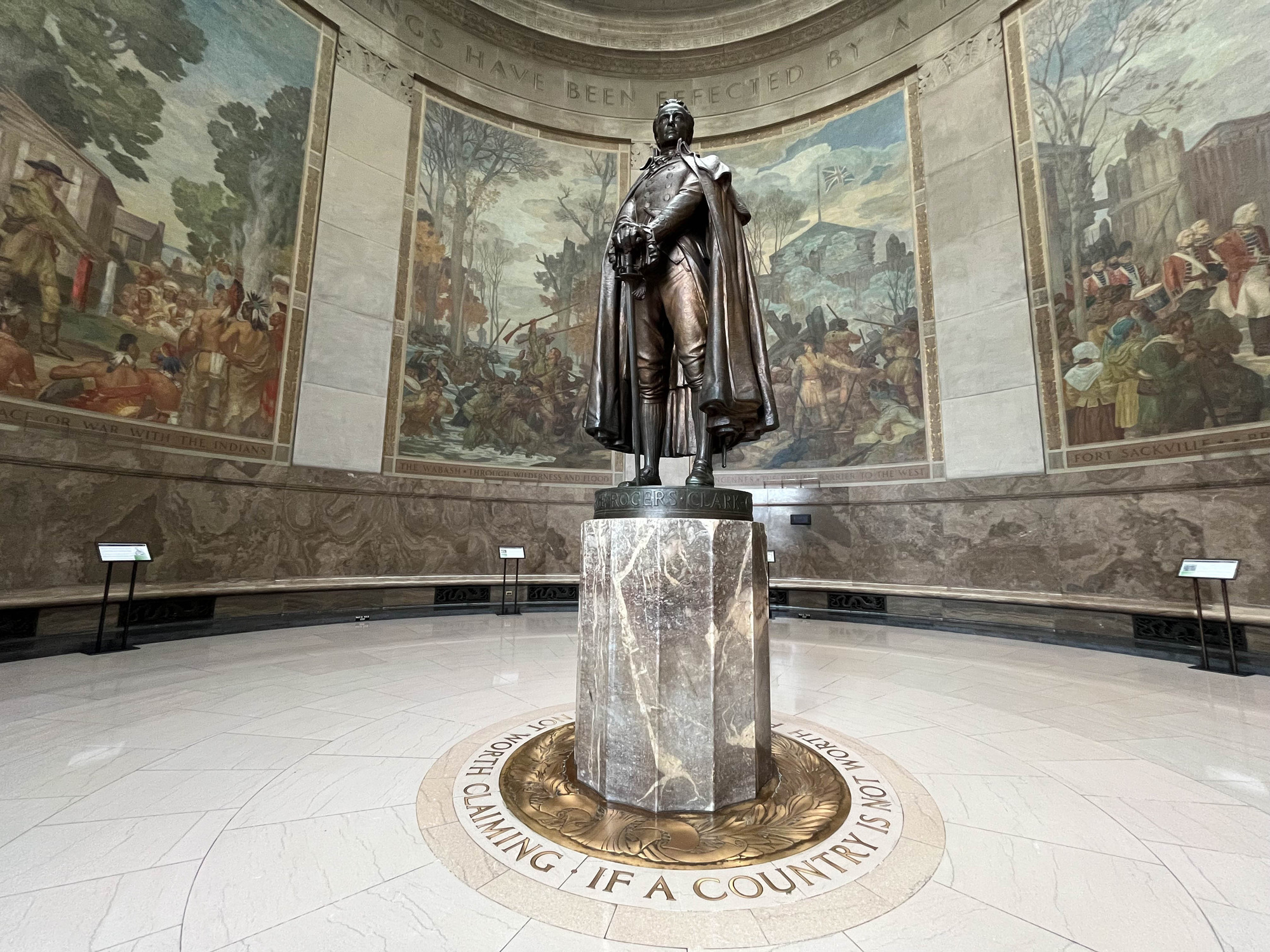 Statue of George Rogers Clark in a memorial's rotunda decorated with paintings of historical events 