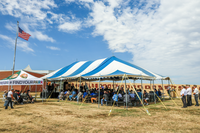School choir sits under small tent on left with 