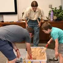 Union soldier, a man and boy digging through the archeology station.