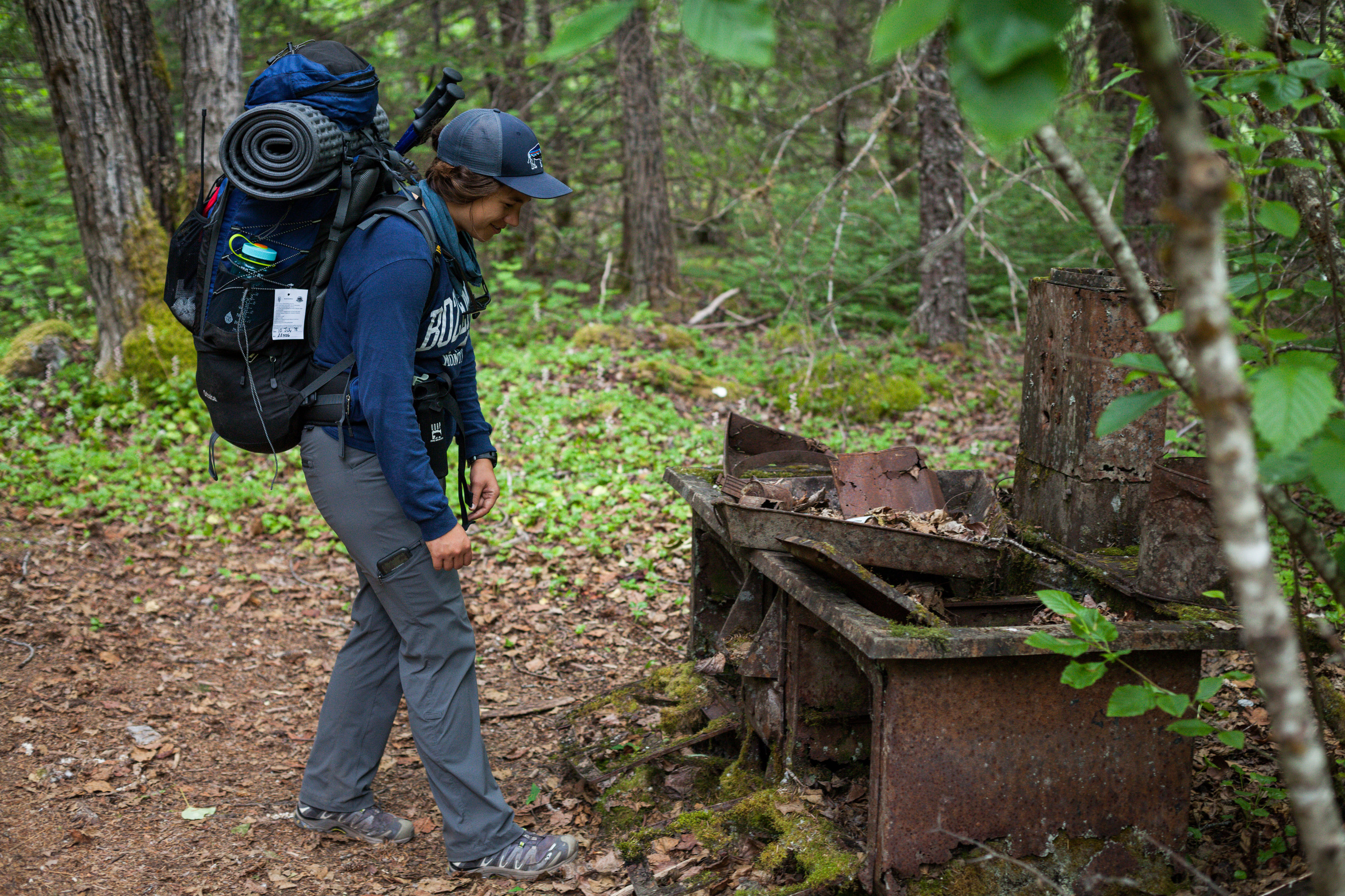 A backpacker examines a rusty shell of a stove