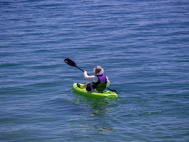 kayak pilot with paddle raised surrounded by blue water