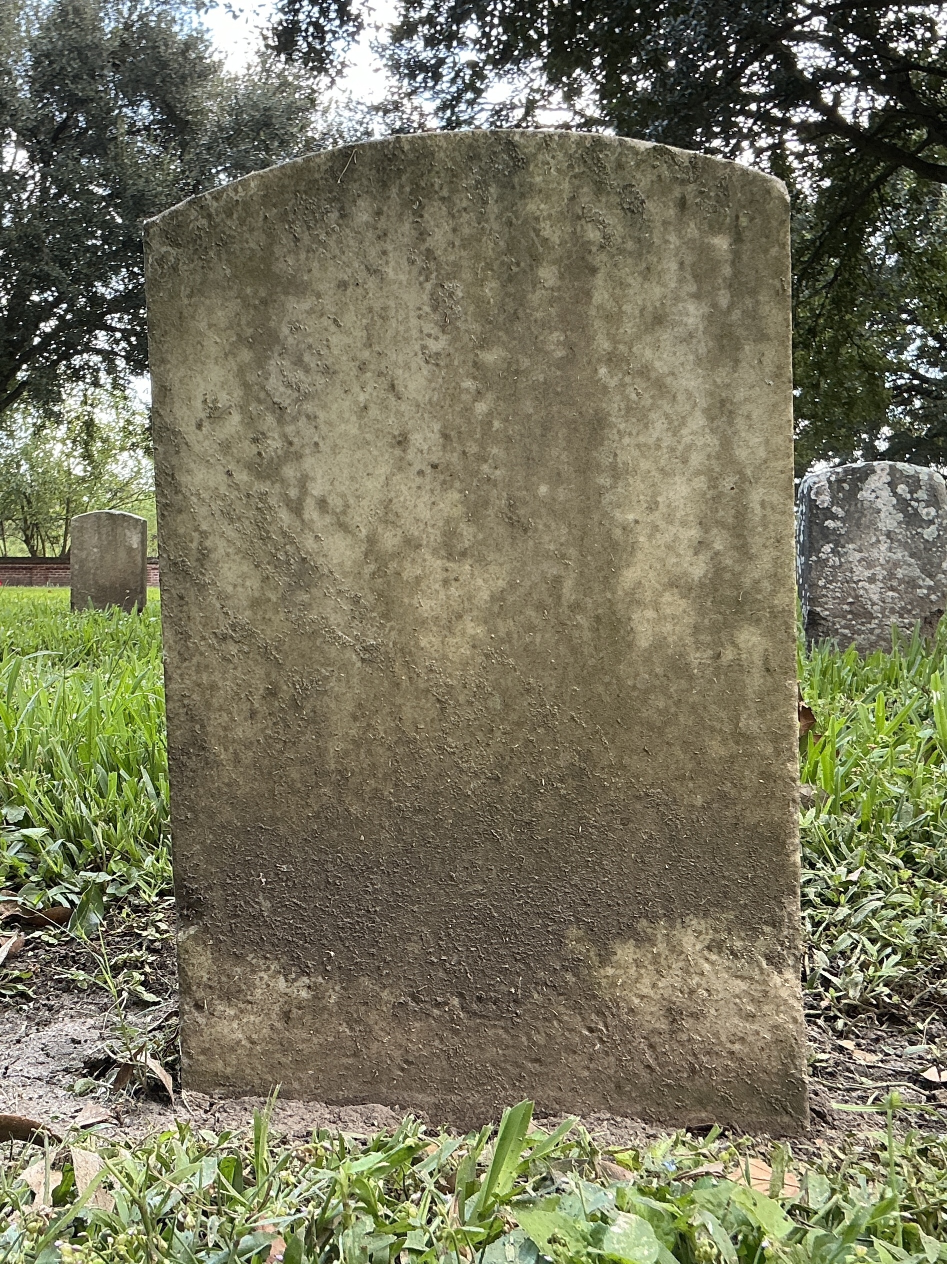 Back of historic upright marble headstone with recessed shield face.