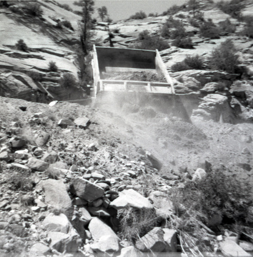 Dump truck dumping gravel for building and repairing retaining wall along East Rim road.