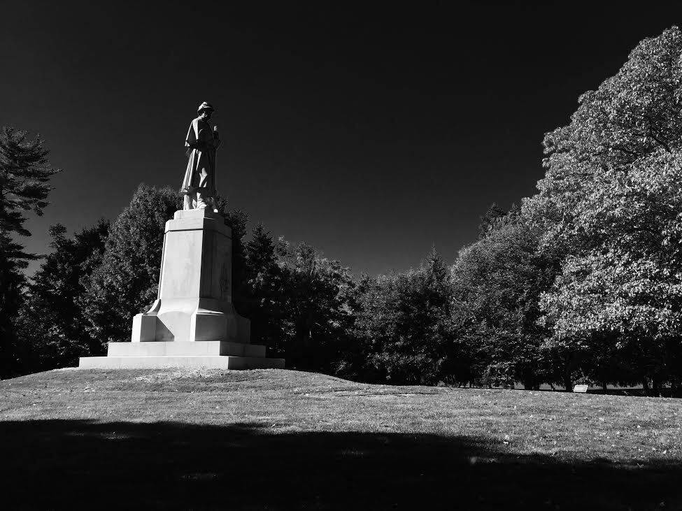 black and white photo of soldier on top of a granite monument