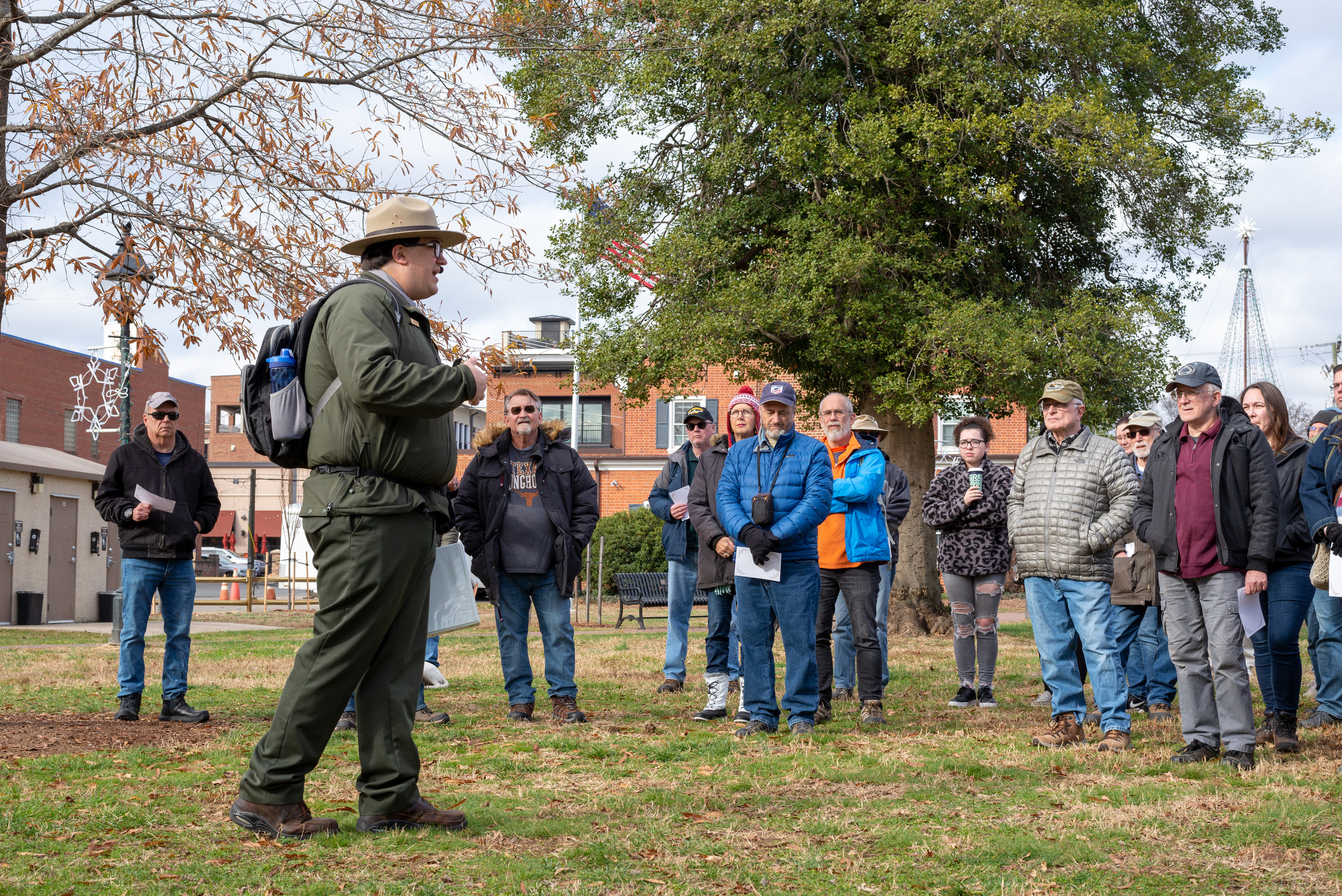 A park ranger stands in a clearing speaking to a group of people.