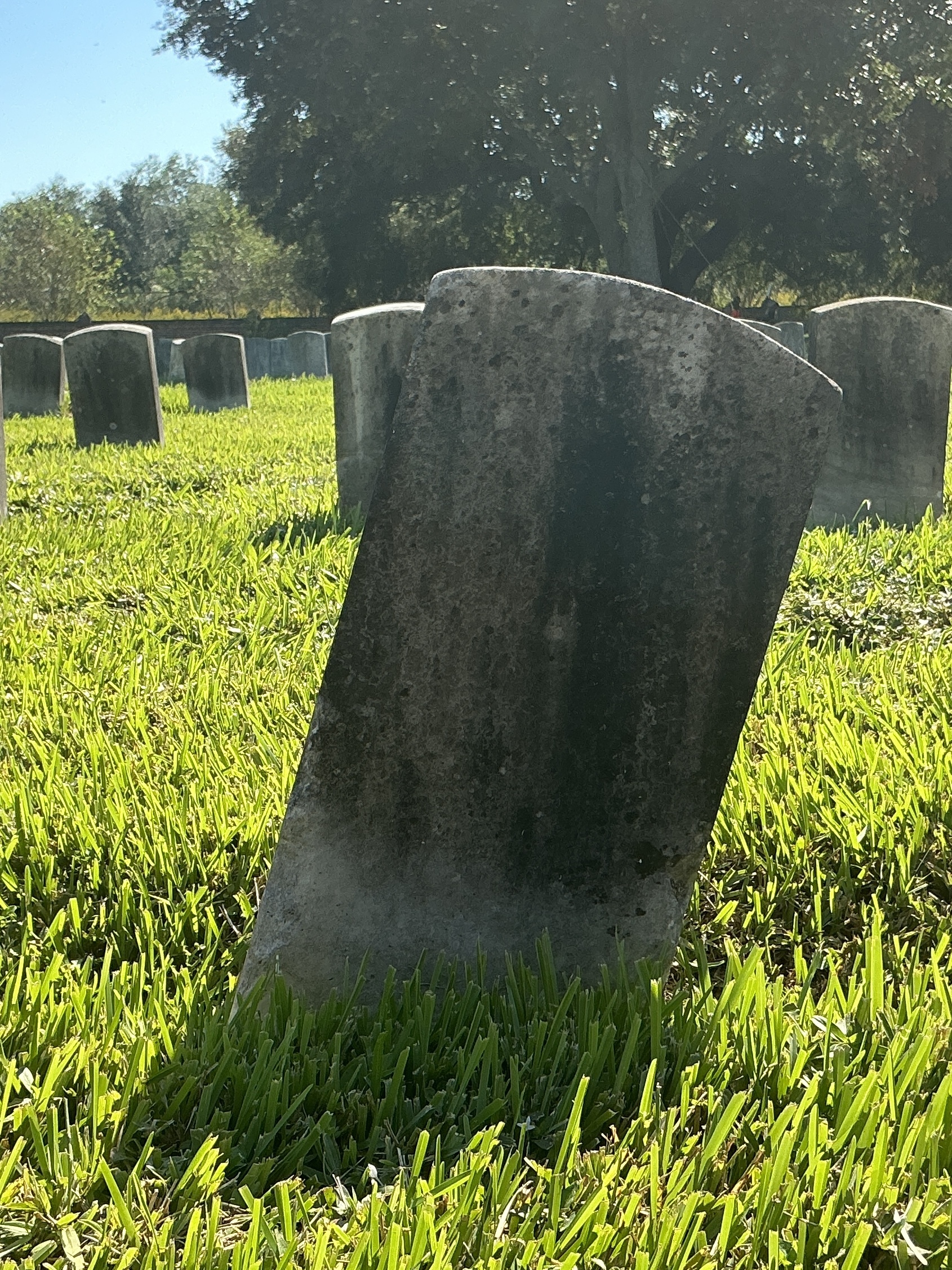 Back of historic upright marble headstone with recessed shield face.
