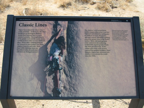 There is an outdoor exhibit with an image of a rock climber on light-colored granite rock. She is next to a crack holding onto lines and folds in the rock. The text on the wayside is described in the body text above. Additional text on the exhibit reads, Hemingway Buttress offers climbers fine-crack climbs and established descent paths for rappelling. Whimsical route names like Poodles are People too White Lightning, and The Importance of Being Ernest identify some of the more challenging and popular climbs here. 