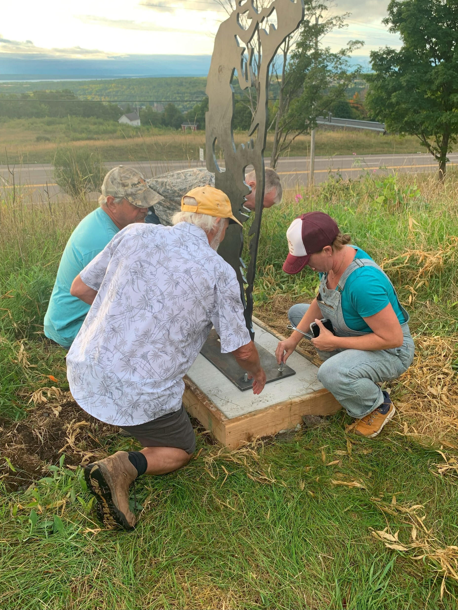 Artist Kasey Koski and others add bolts to secure the "Waving Miner" statue to its base. 