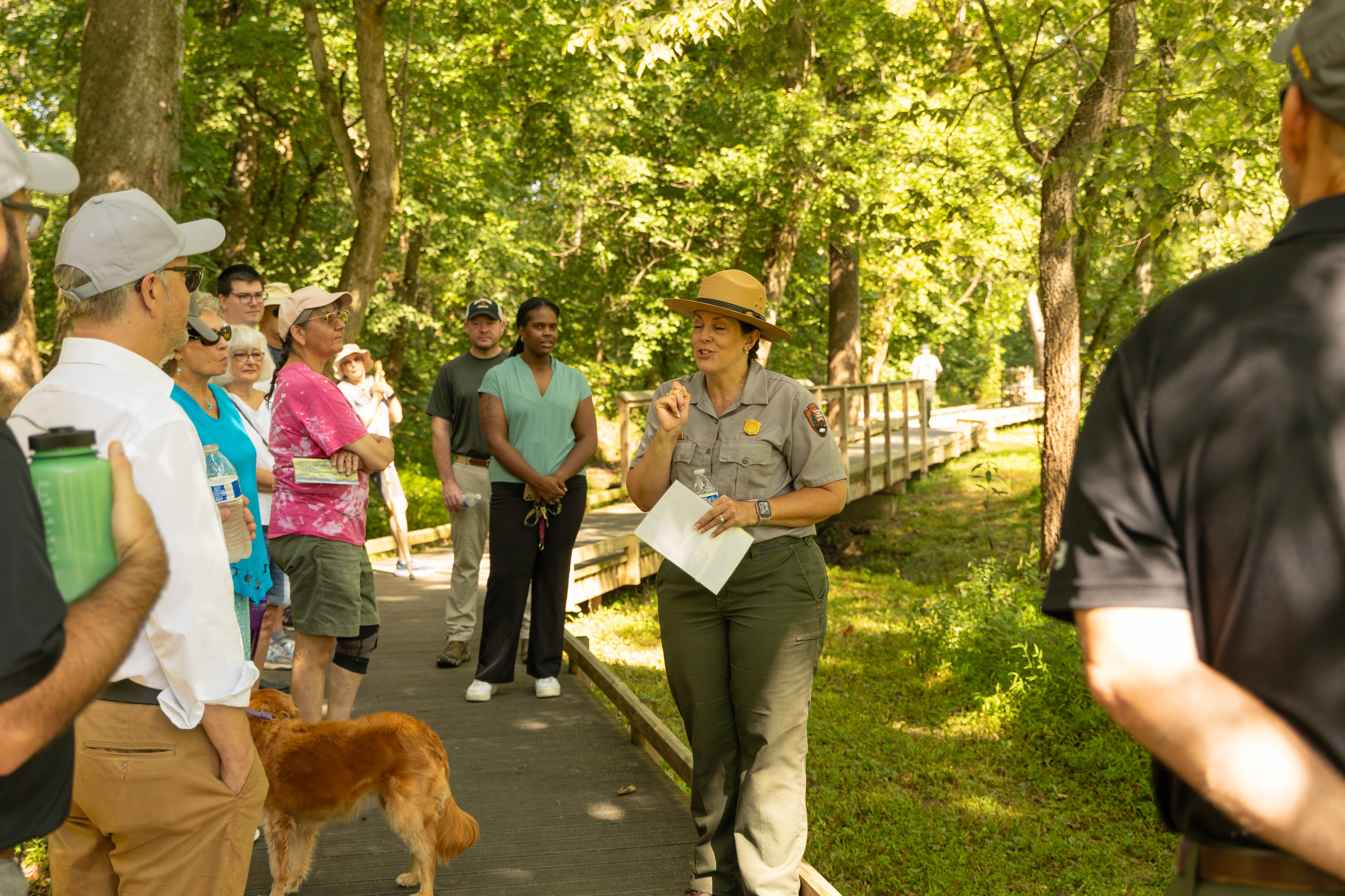 A park ranger in uniform leads a walking tour on a boardwalk. 