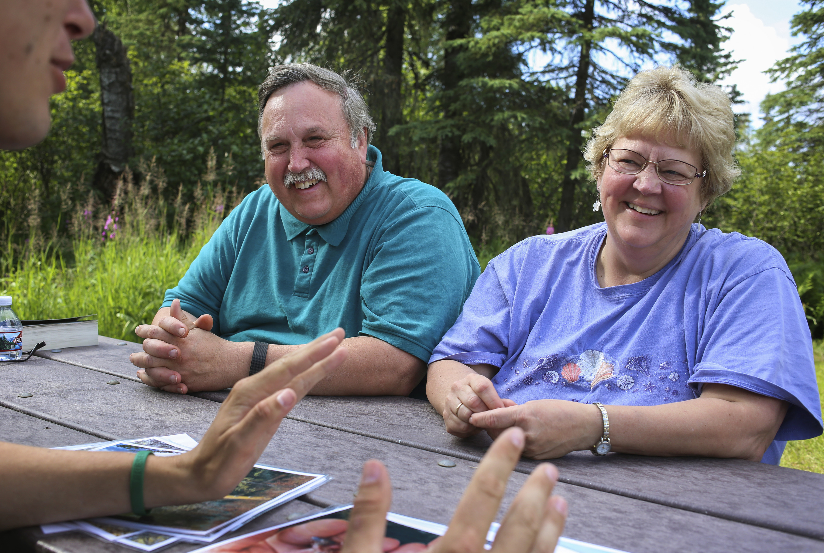 a park ranger speaks to two people at a picnic table