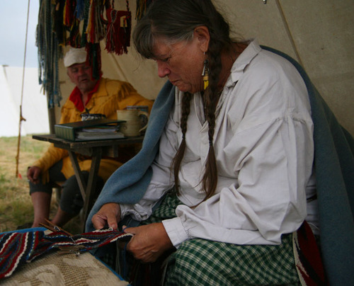 Seated woman holds half made sash with blue, red and white stripes