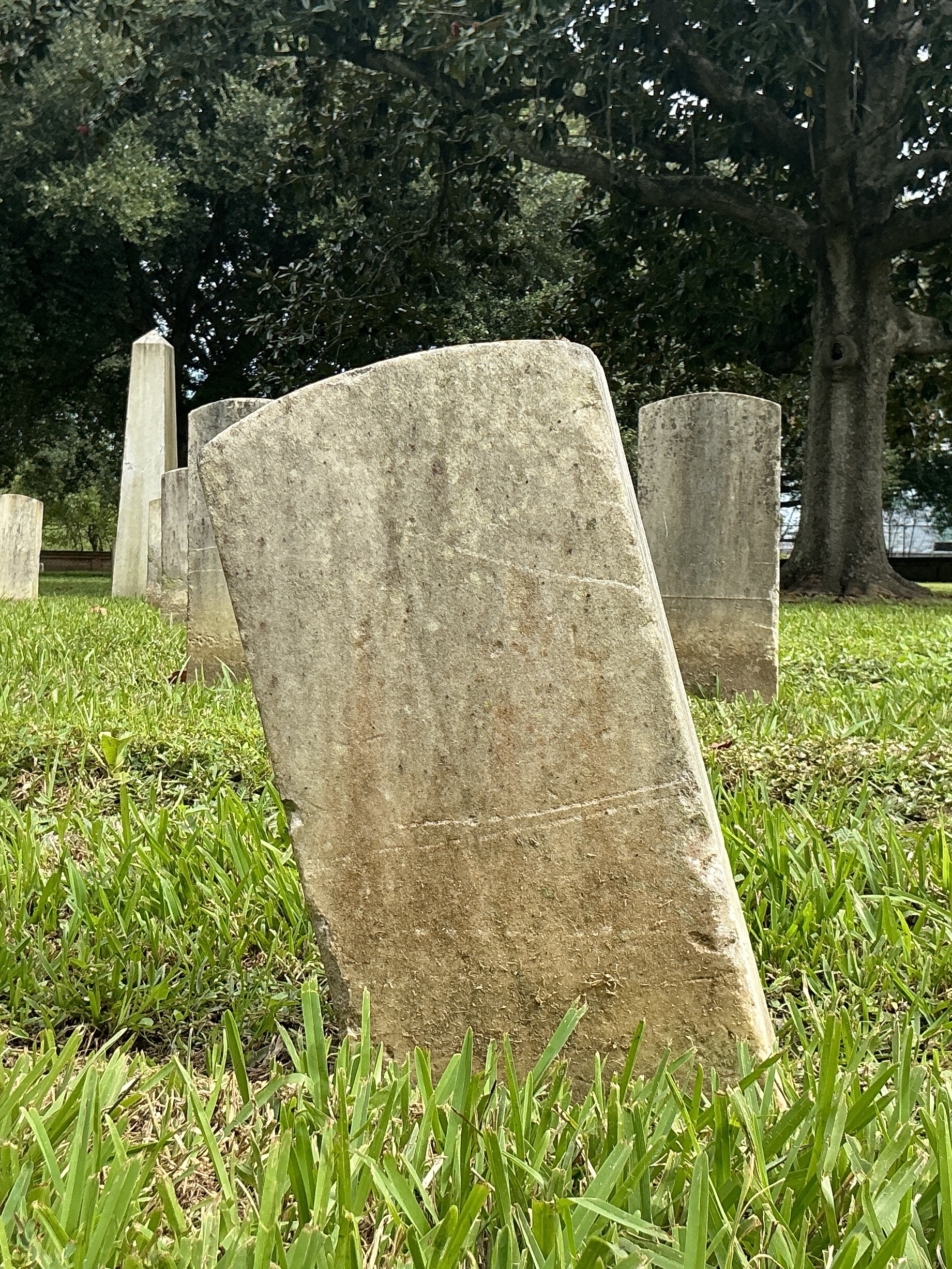 Back of historic upright marble headstone with recessed shield face.