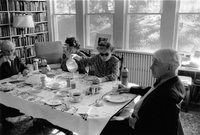 Four adults sitting around table eating breakfast