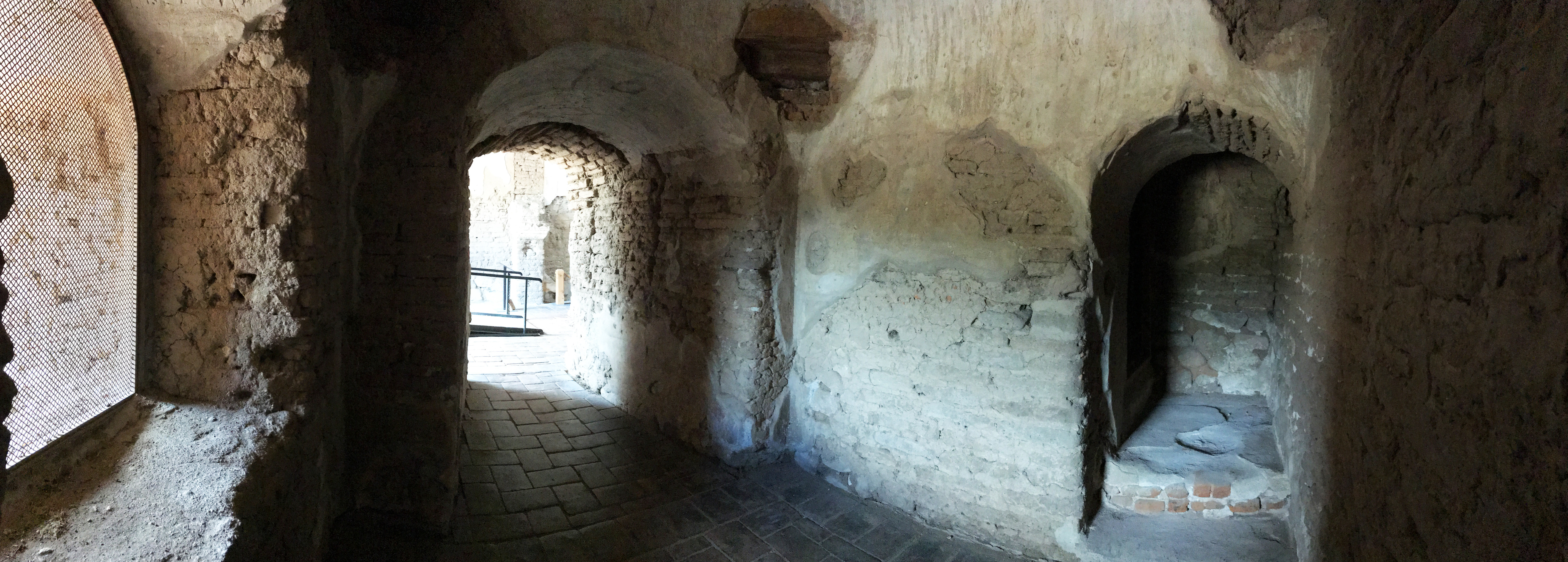 panoramic view of interior baptistry with window to the right, passageway ahead, and dark staircase to the right