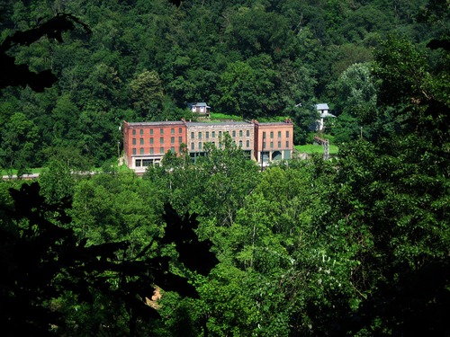 a view through the forest of a row of brick buildings
