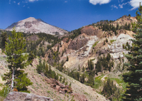 Lassen Peak from the Main Park Road. View of Lassen Peak rising above the rocky, colorful cliffs below in Little Hot Springs Valley with the Main Park Road to the left.