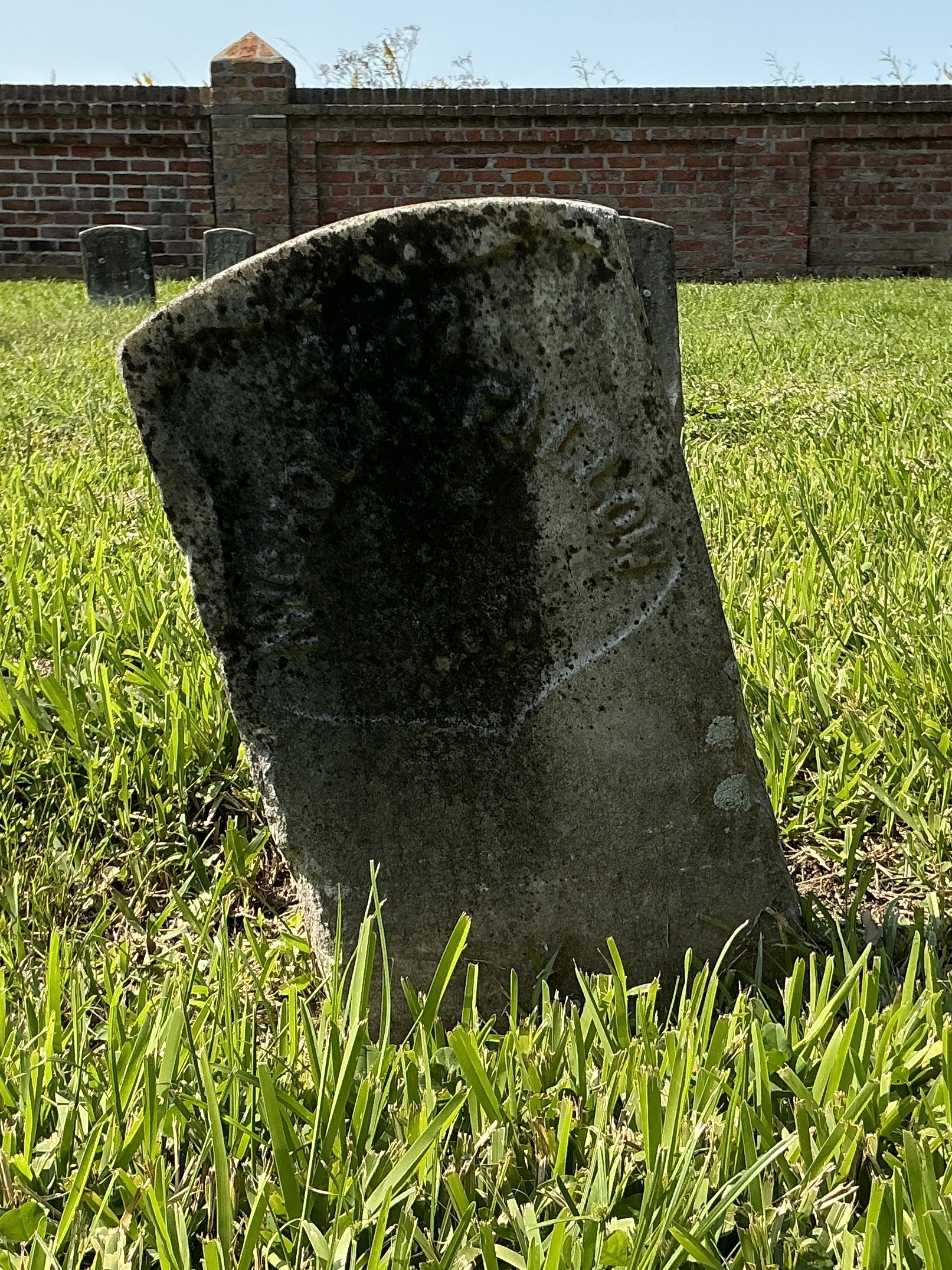 Front of historic upright marble headstone with recessed shield face.