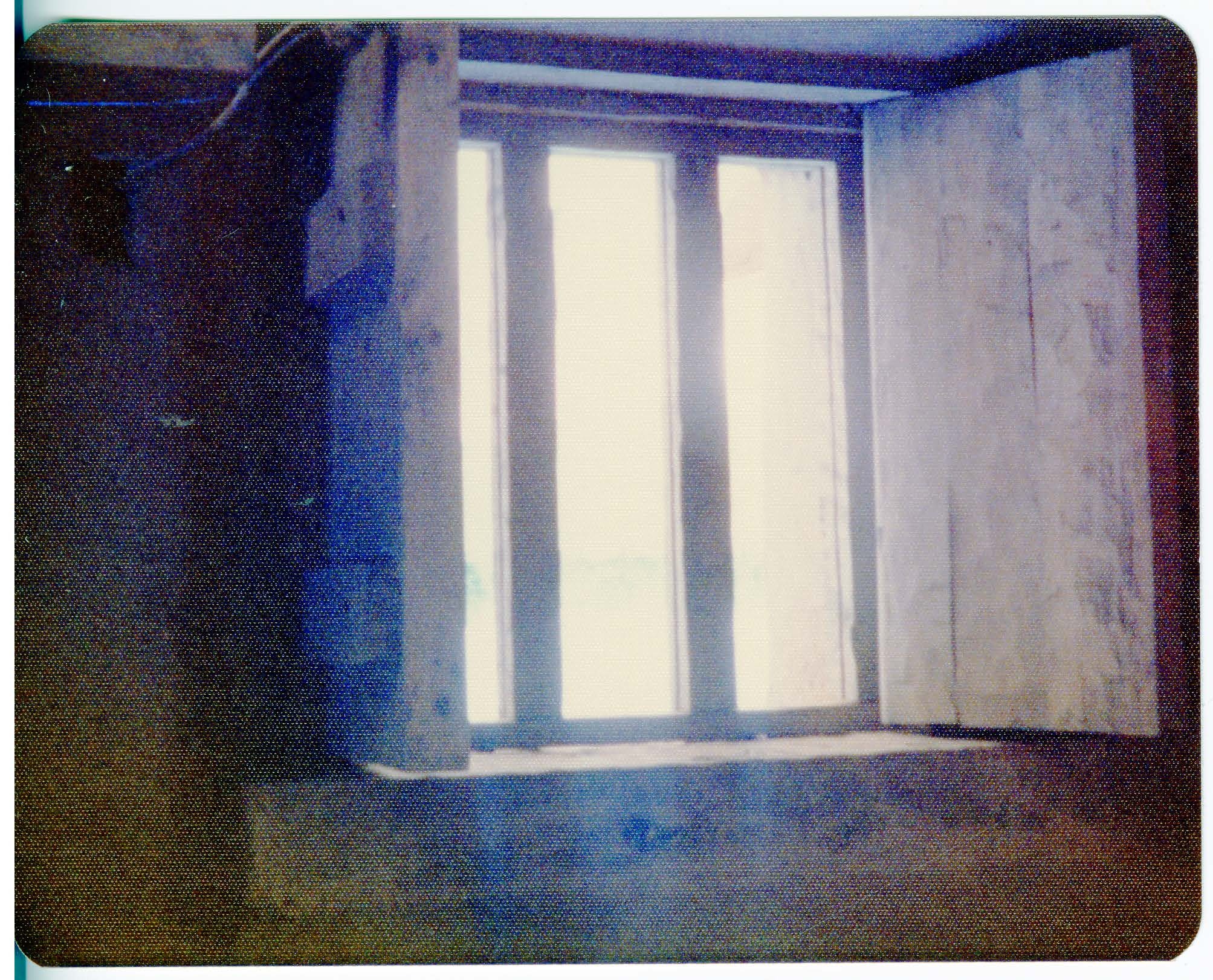 An open wooden window allows light into a dark room.