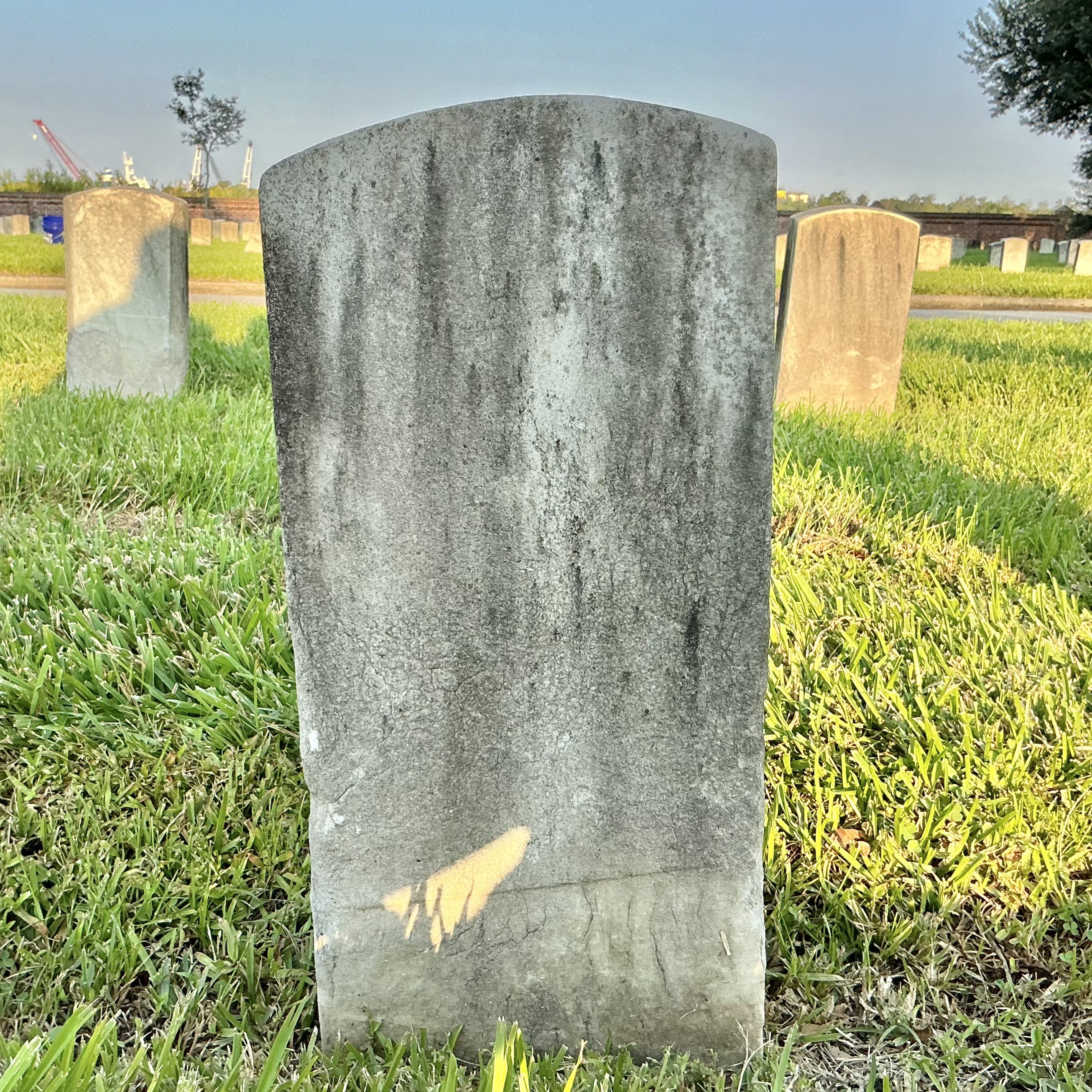 Back of historic upright marble headstone with recessed shield face.