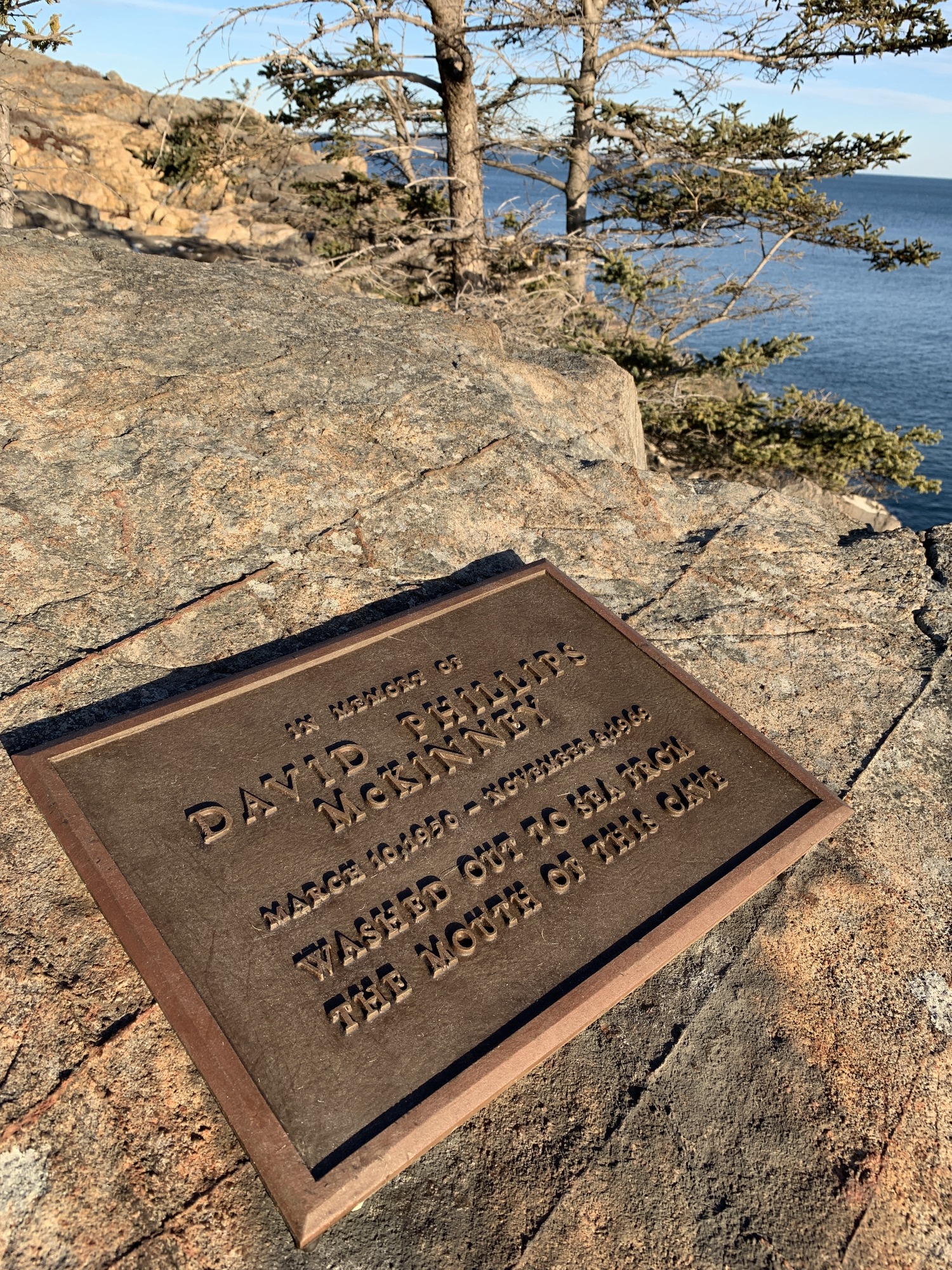 Bronze plaque on ocean cliff reads: In memory of David Phillips McKinney, March 10, 1950-November 8, 1969, washed out to sea from the mouth of this cave.