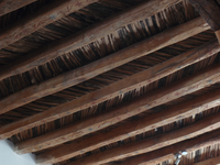 The ceiling of a room with wooden beams.