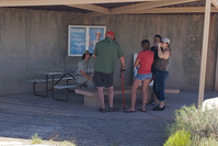 Uniformed woman with four people under a shelter with a poster in back.
